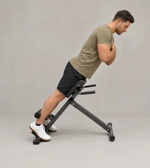 A man on a 45-degree back-extension bench with his hips resting on the pad, the top edge of the pad just below the hip crease.